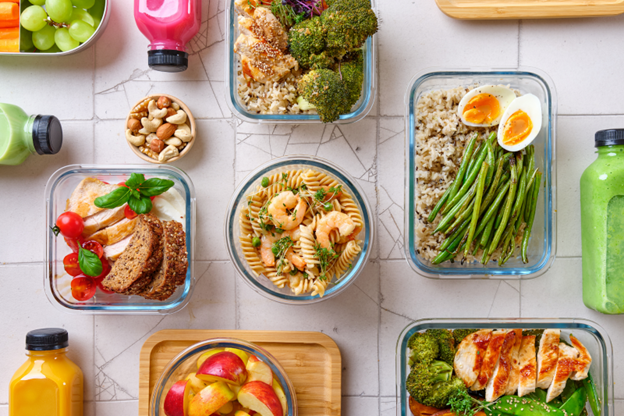 Assortment of healthy food made up of different meals, snacks such as mixed nuts, fruit, and cold-pressed juices.